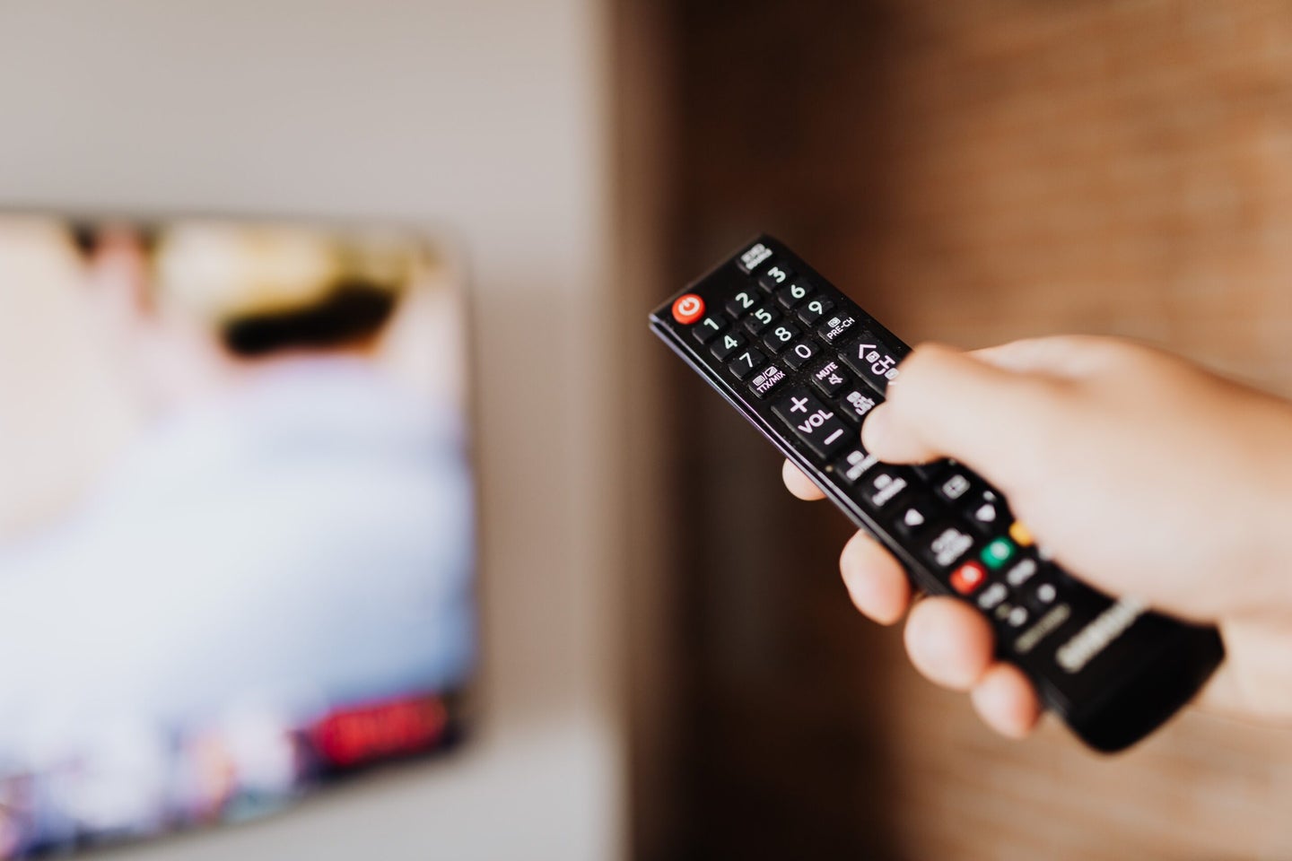 Person clicking button on TV remote