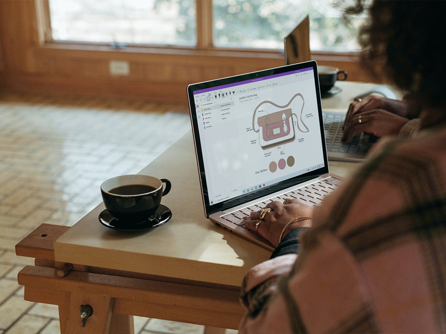 A person designs a purse on a laptop using a Microsoft program.