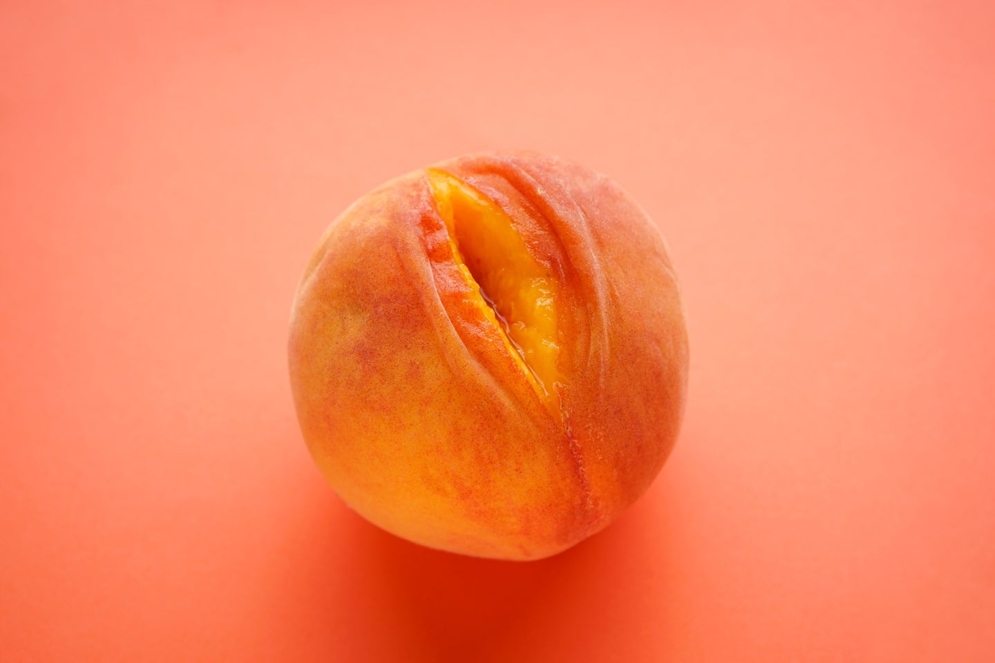 Juicy peach with slit to represent vabbing on an orange background