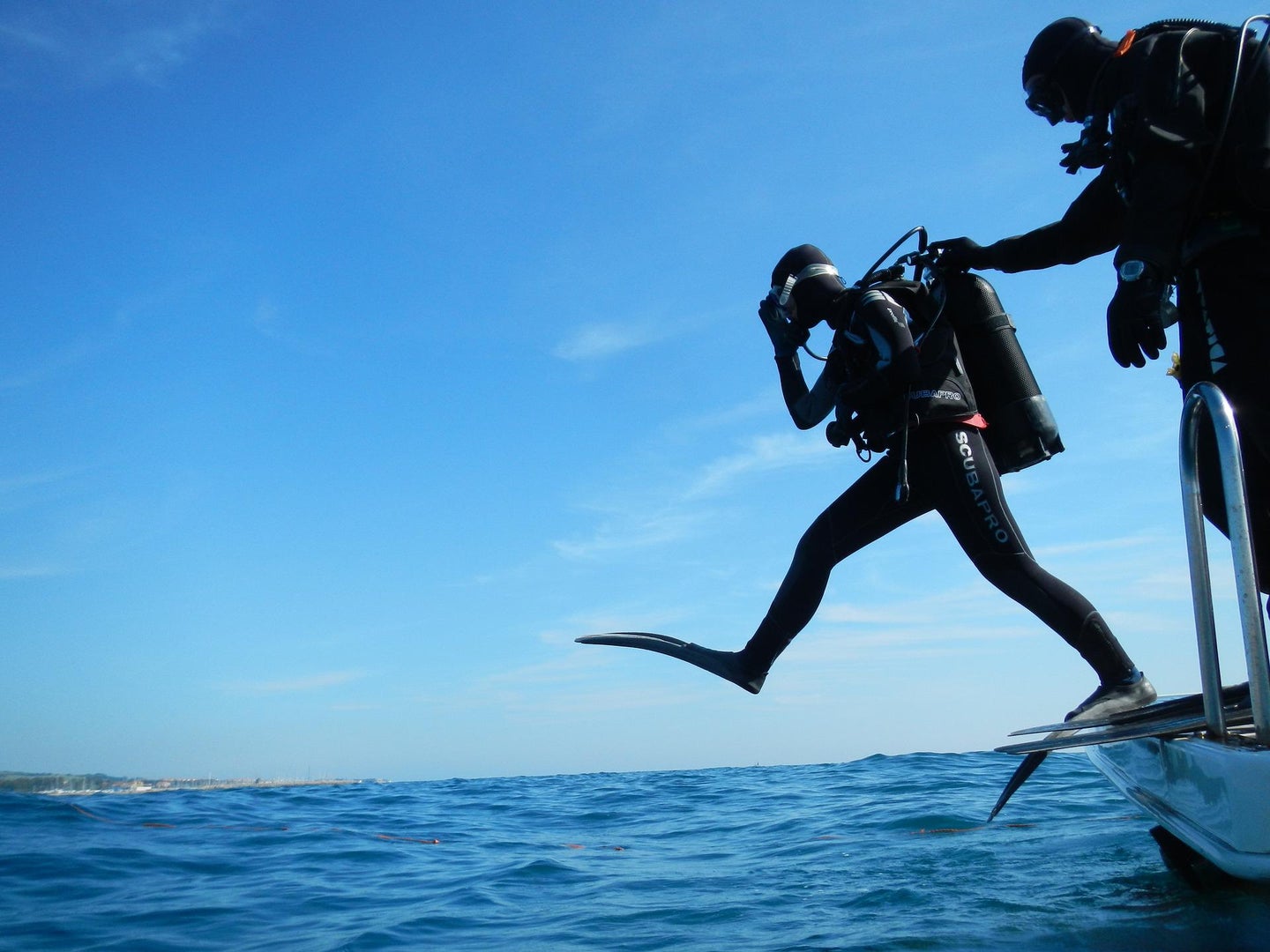 A scuba diver takes a step into the ocean.