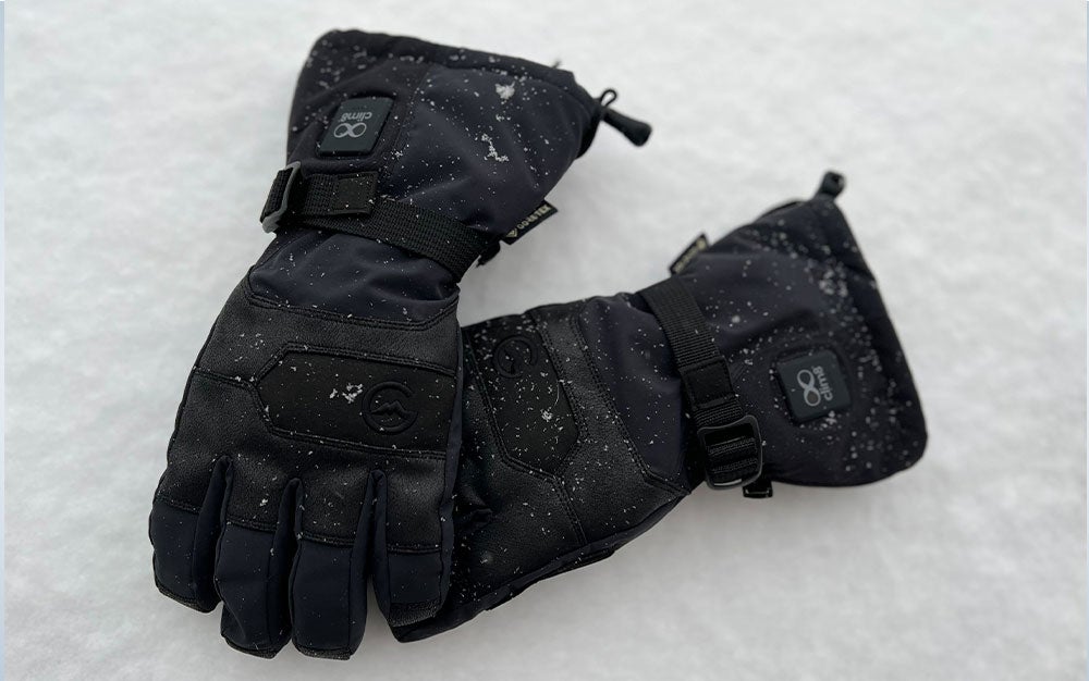 A black pair of Gordini Forge Heated Gloves laying in the snow.
