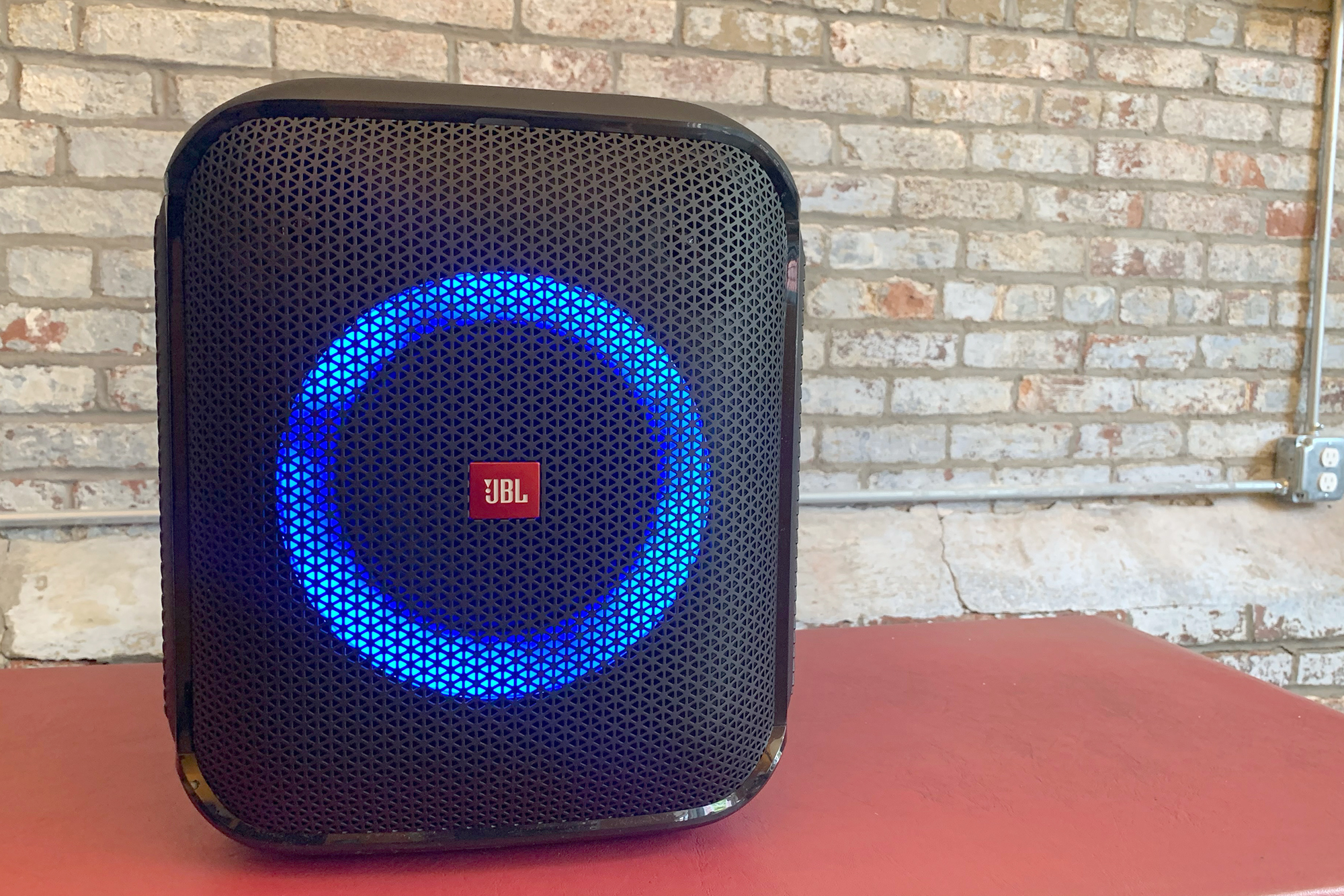 JBL PartyBox Encore Essential blue LED light show on a red table