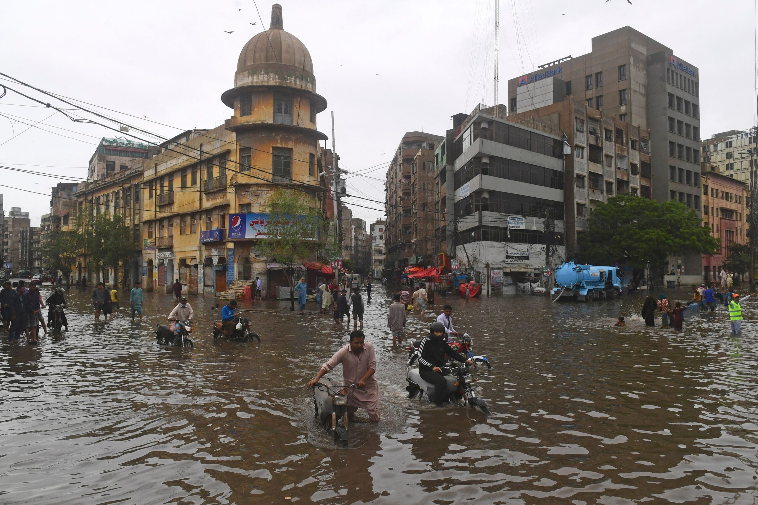 People wade across a flooded street after heavy monsoon rainfall in Karachi on July 25, 2022