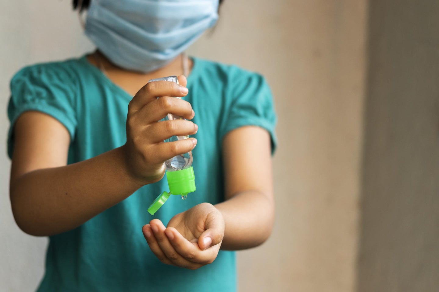 A child wears a mask and sanitizes hands to avoid getting sick.