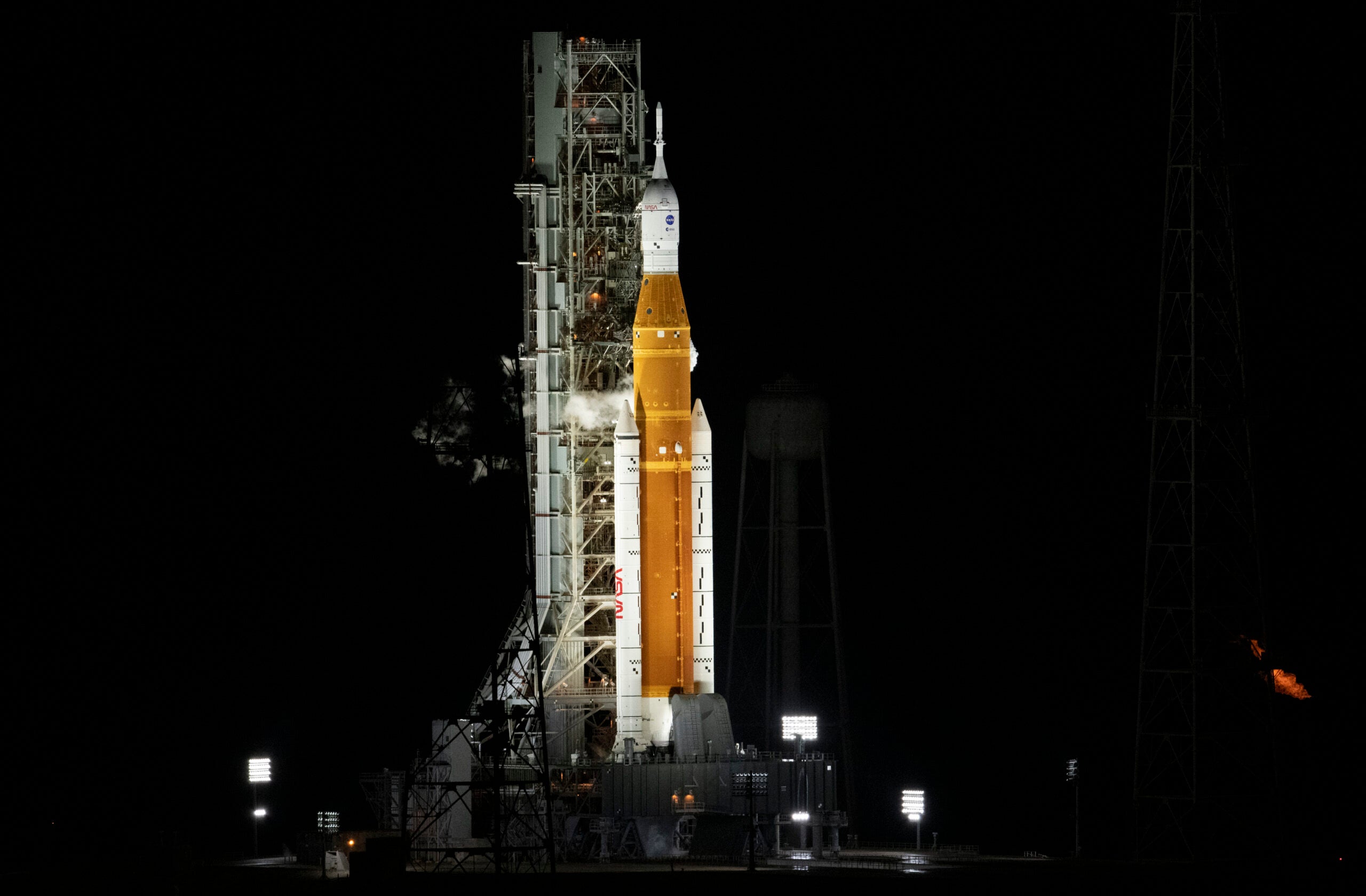 NASA orange SLS rocket with Orion spacecraft on top at Kennedy Space Center launch pad