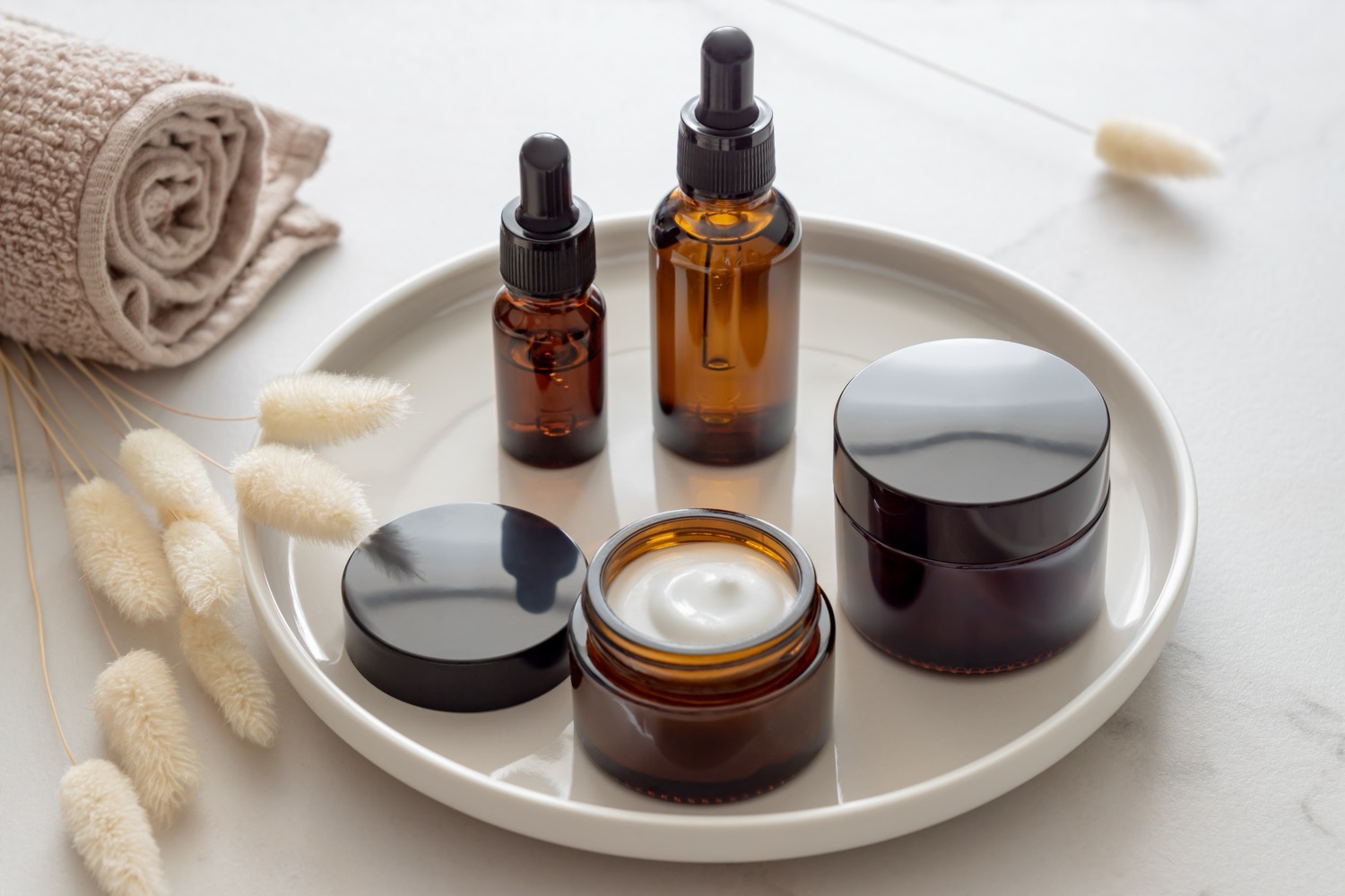 Set of different cosmetic bottles of cream or serum on a ceramic tray