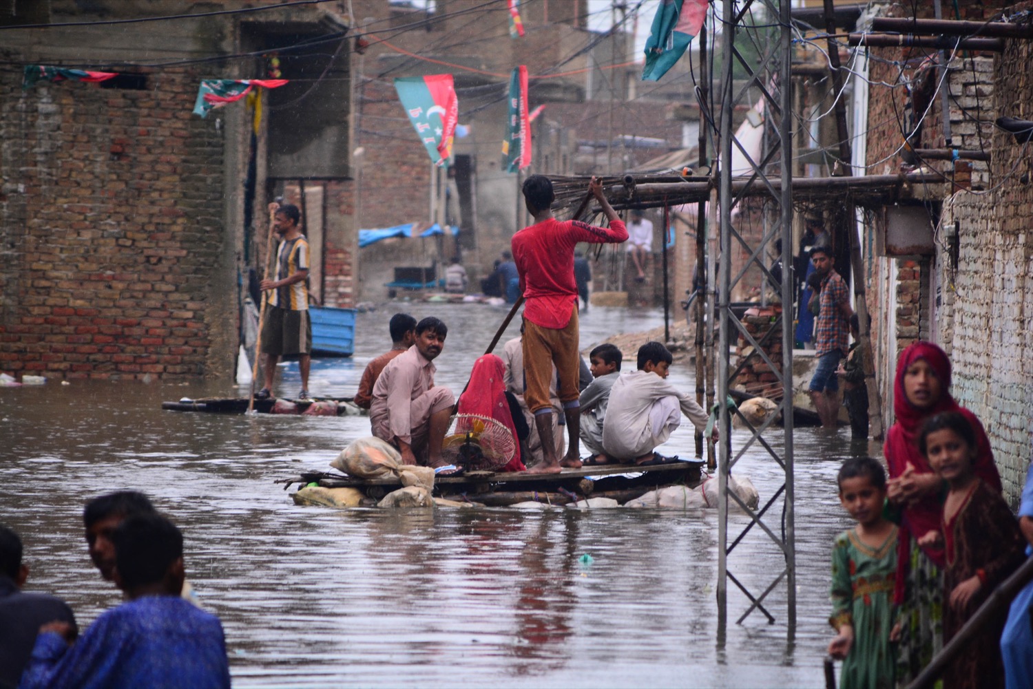 people sit on a makeshift raft and row down flooded streets in pakistan