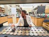 a man in a lab coat looks at various petri dishes filled with fungi under a lab hood