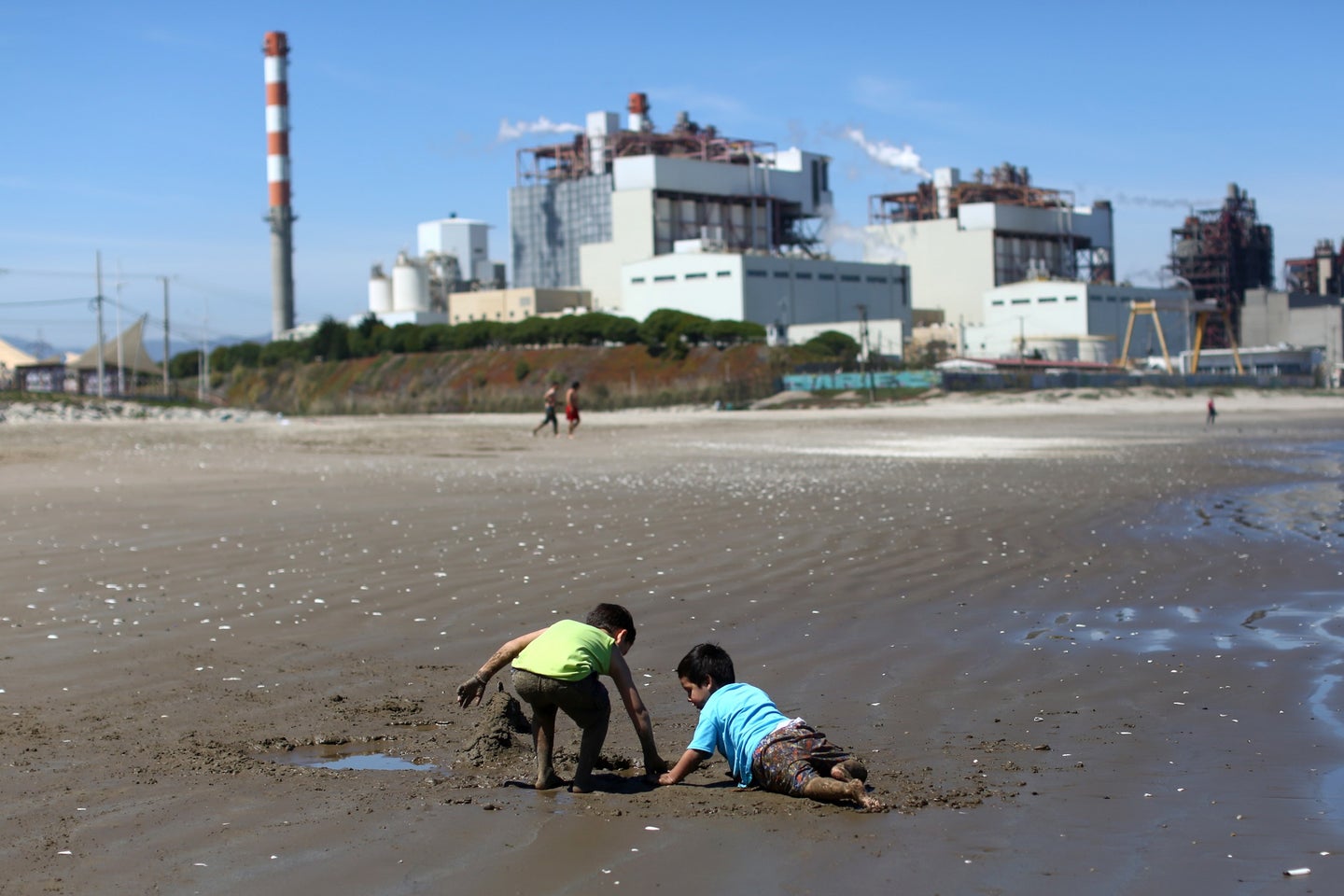 Children playing in polluted sand in front of AES Gener thermoelectric plant in Chile