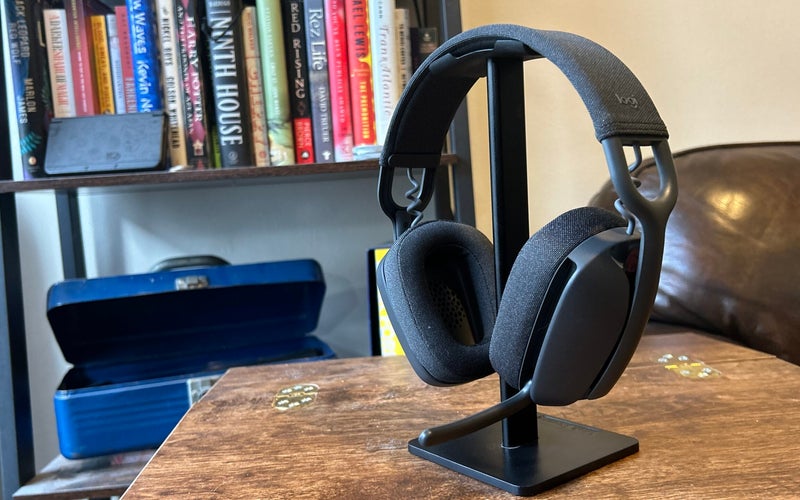 The Logitech Zone Vibe 100 hangs from the headset, which sits on a headphone stand