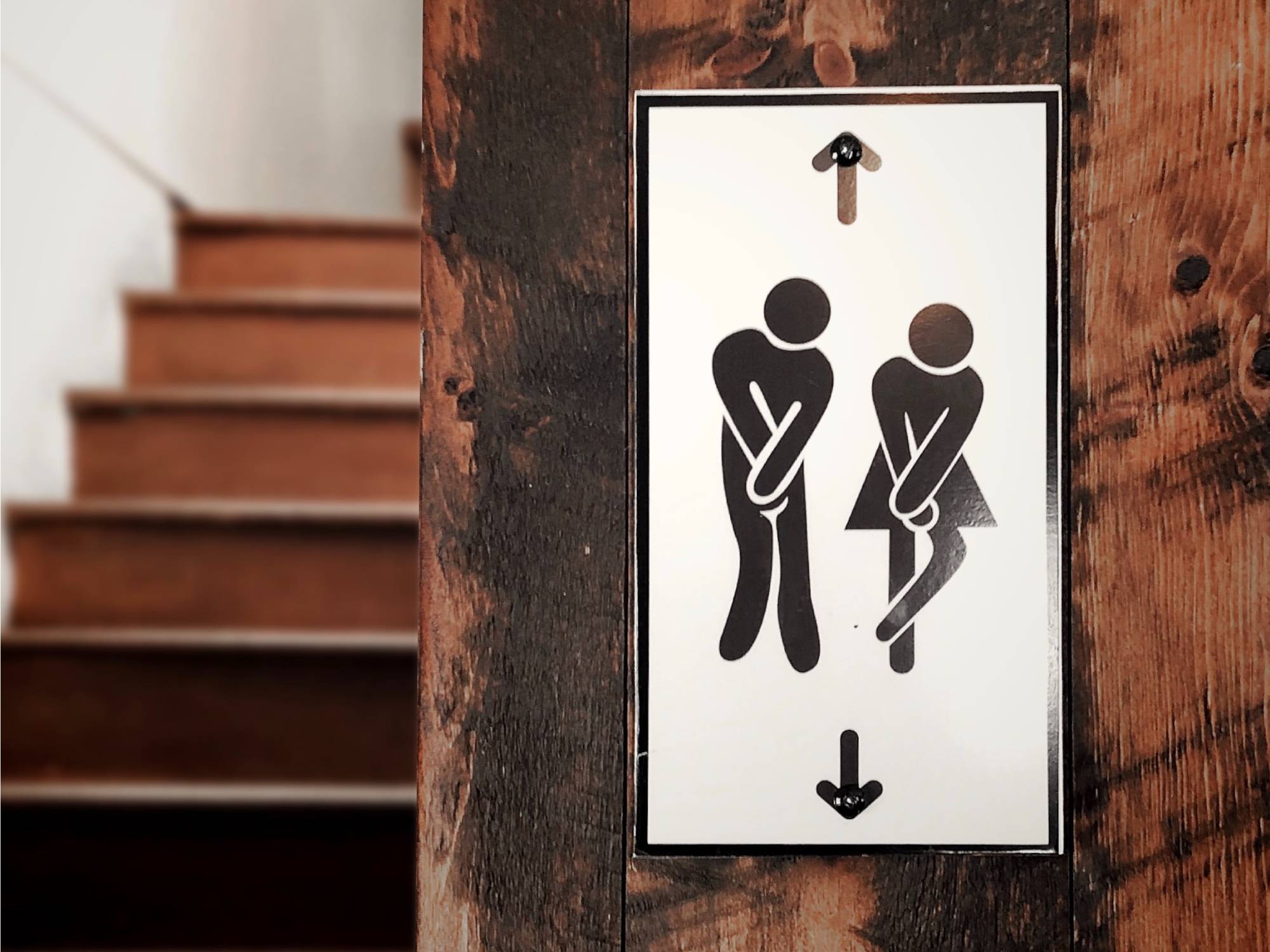 Restroom sign with figures in a holding position