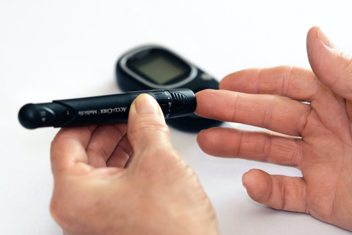 a person with diabetes uses a lancet to poke their finger to check blood sugar levels