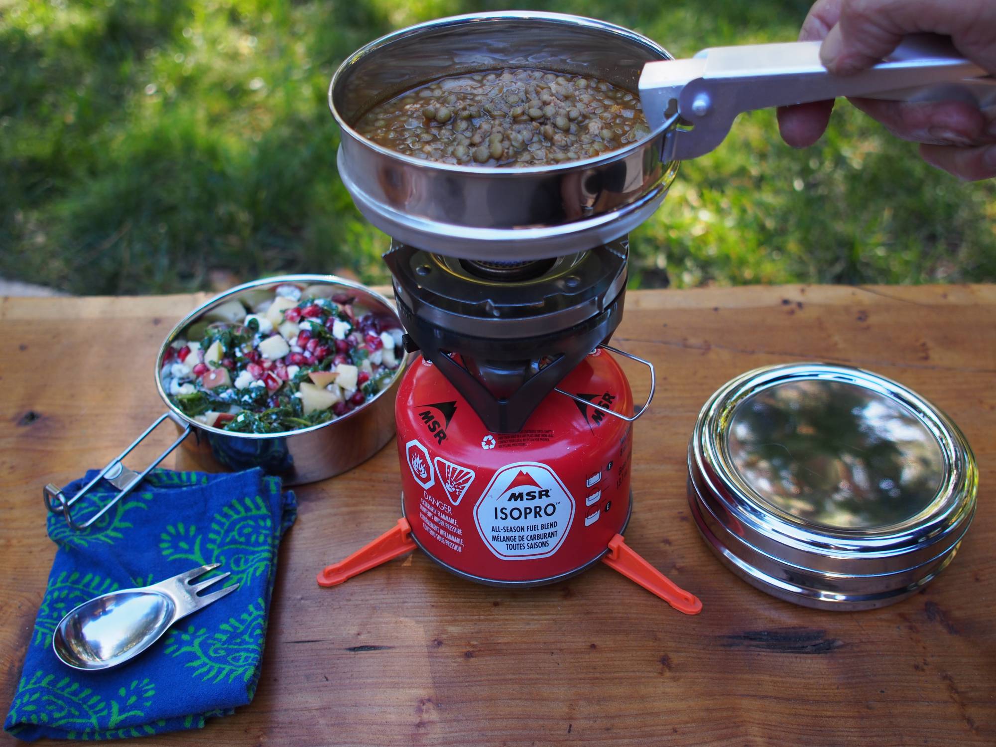 hand holding pot with lentils on camp stove