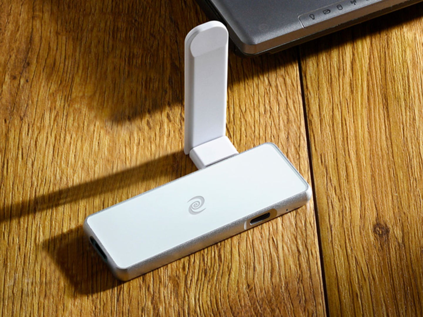 A white VPN and cybersecurity device on a light brown wooden table