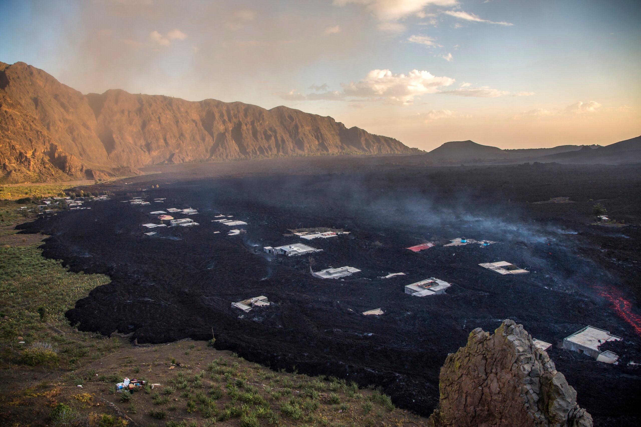 Black lava and ash covering an island village at sunrise