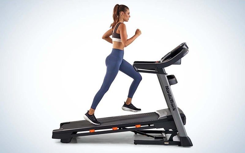 A woman in a gray jogging bra and leggings running on a NordicTrack T Series Treadmill.