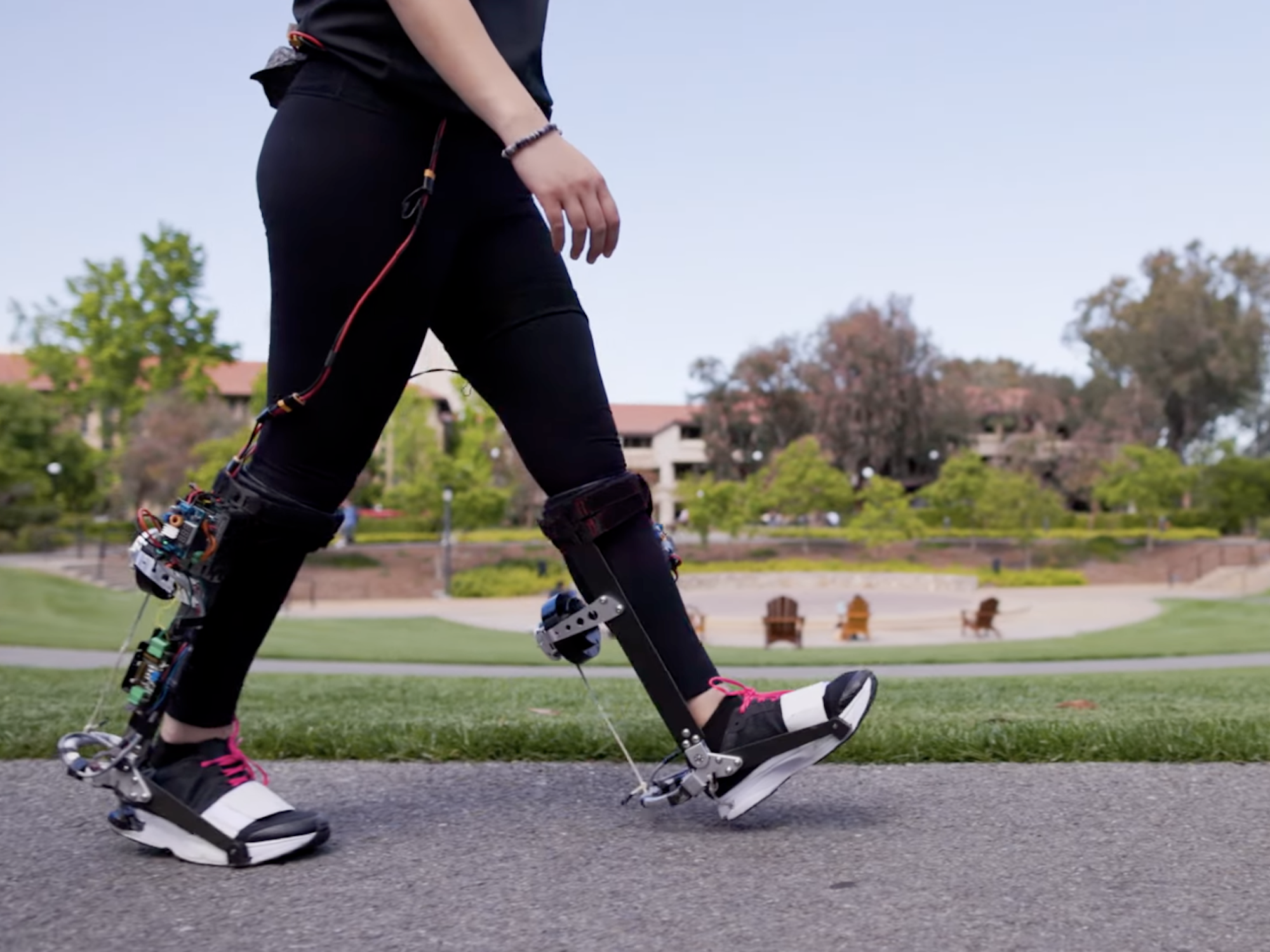 Woman walking across college campus using exoskeleton robotic mobility boots