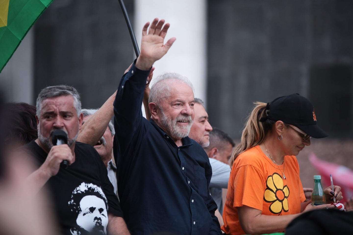 a man with white hair and a short beard waves at a presidential election rally
