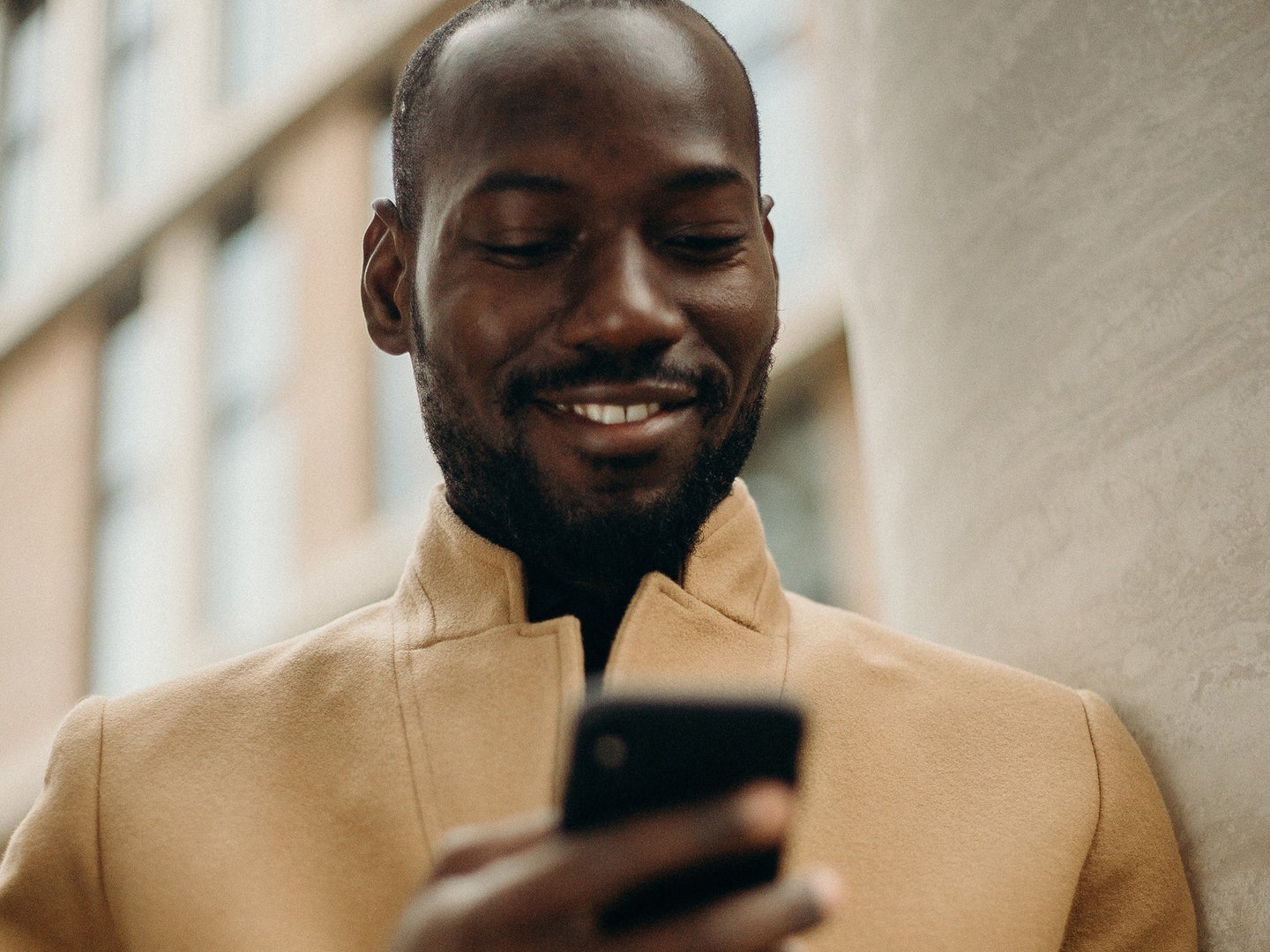 close up of an well dressed black person smiling while looking at their phone