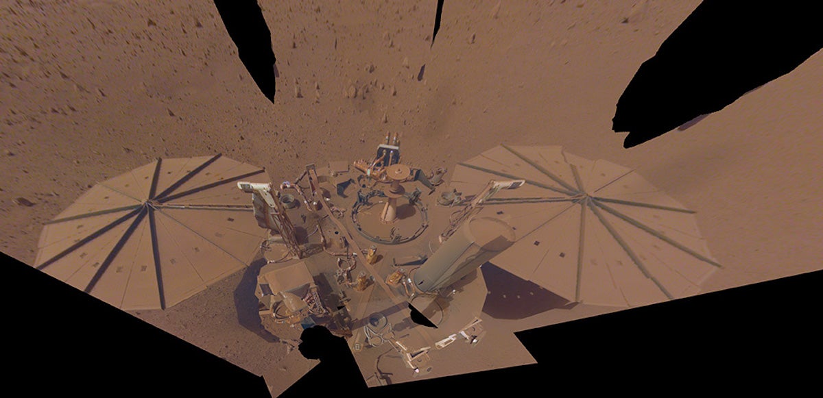 a robot lander covered in orange dust on mars