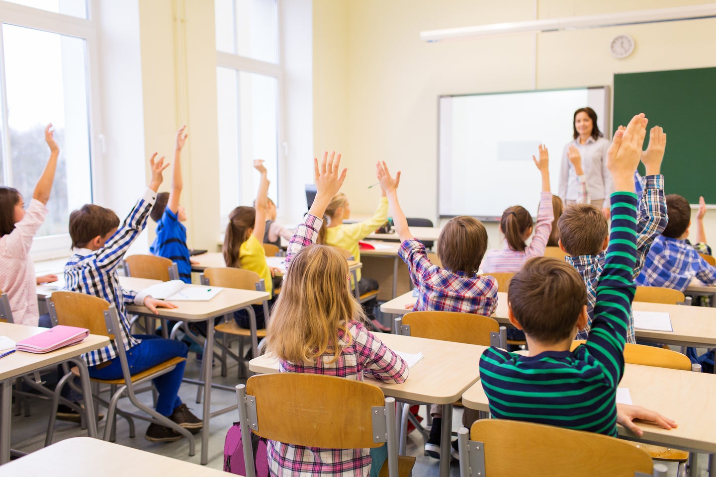 Children raising their hands in a classroom.