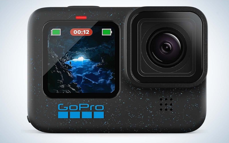 GoPro HERO12 action camera on a plain background with a cave scene on the screen.