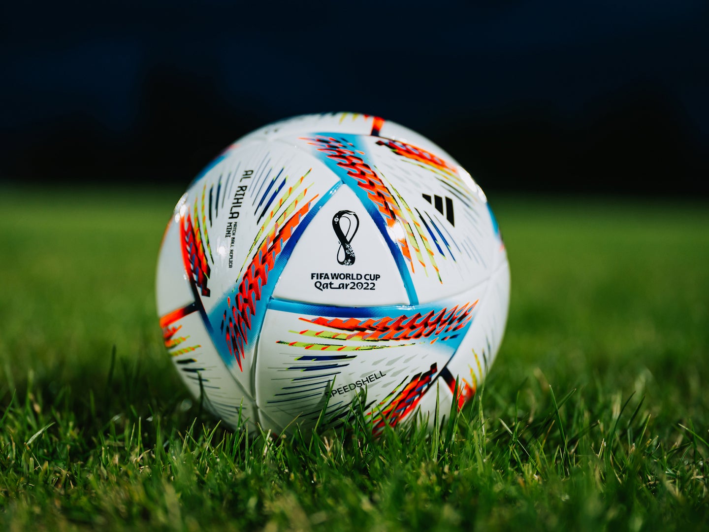 Official Adidas FIFA World Cup soccer ball on green grass in night in stadium
