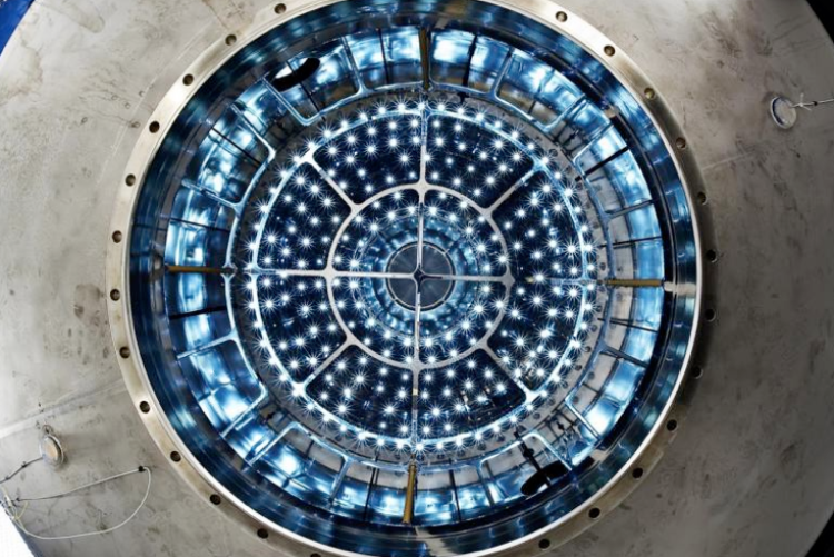 a top down look inside a large chamber with blue lit equipment on the inside
