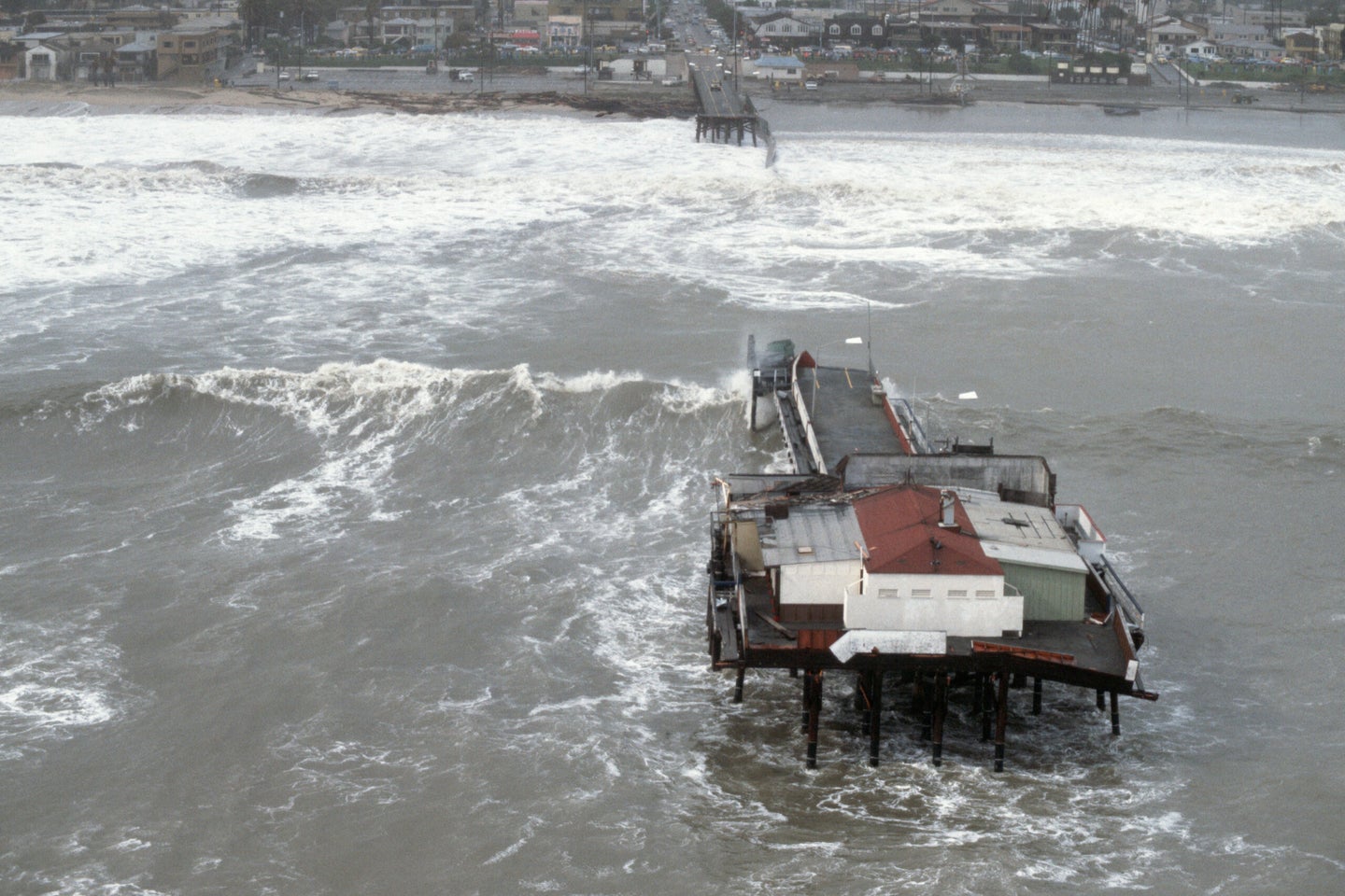 Waves from the El Nino Storm of 1983 crash against a pier off Santa Monica's beach. California, USA.