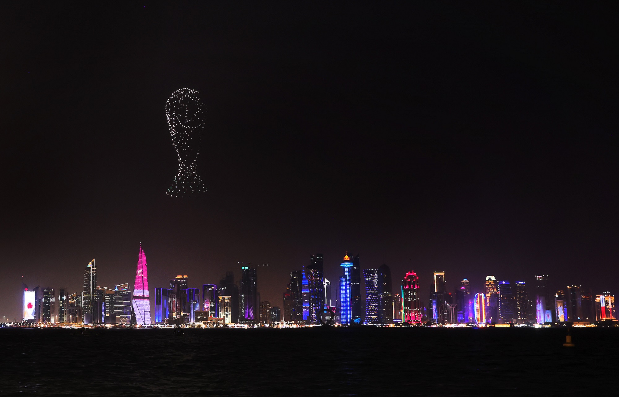 Light show in the night sky over a brightly lit Doha, Qatar during the 2022 World Cup
