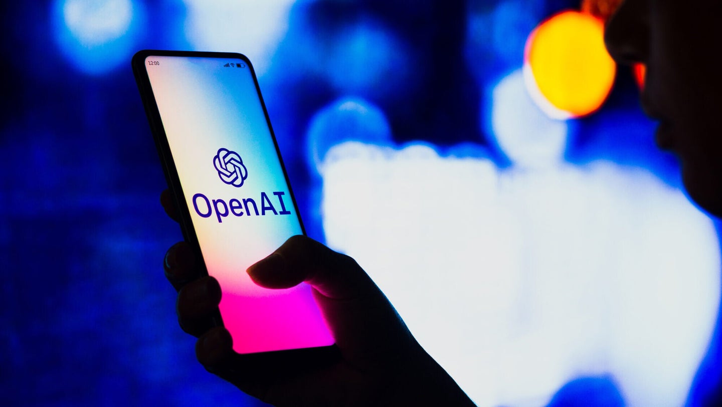 In this photo illustration, a silhouetted woman holds a smartphone with the OpenAI logo displayed on the screen. 