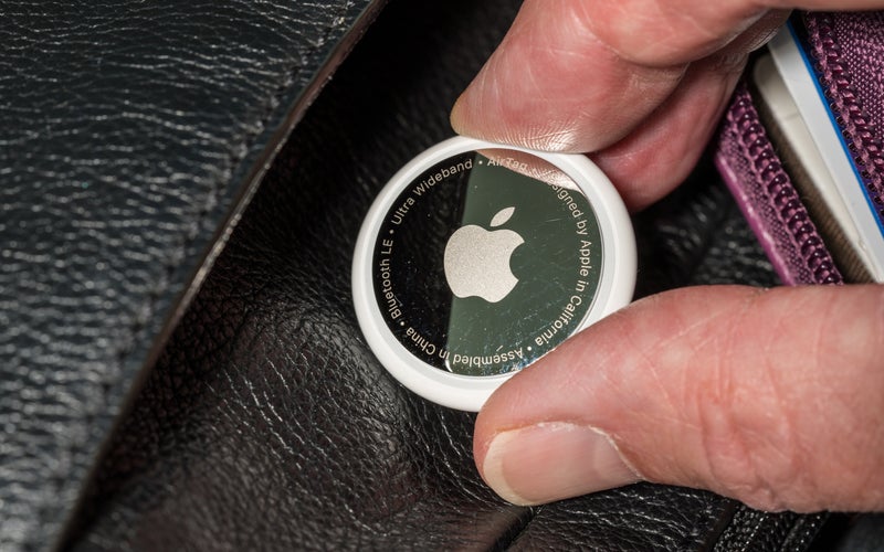 Apple AirTag being inserted into a leather purse