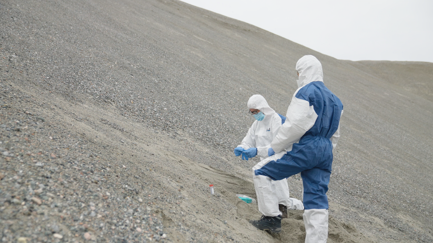 Two scientists in hazmat suits on Greenland's rocky barren Peary Land