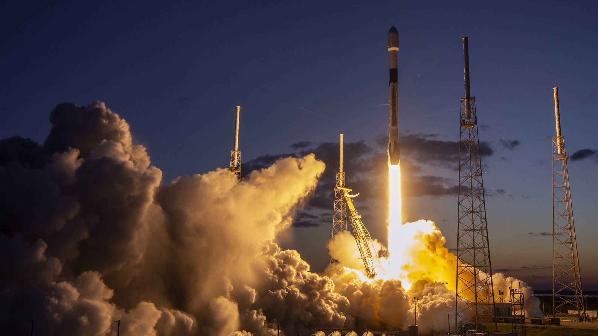 SpaceX rocket lifting off from launchpad at dawn