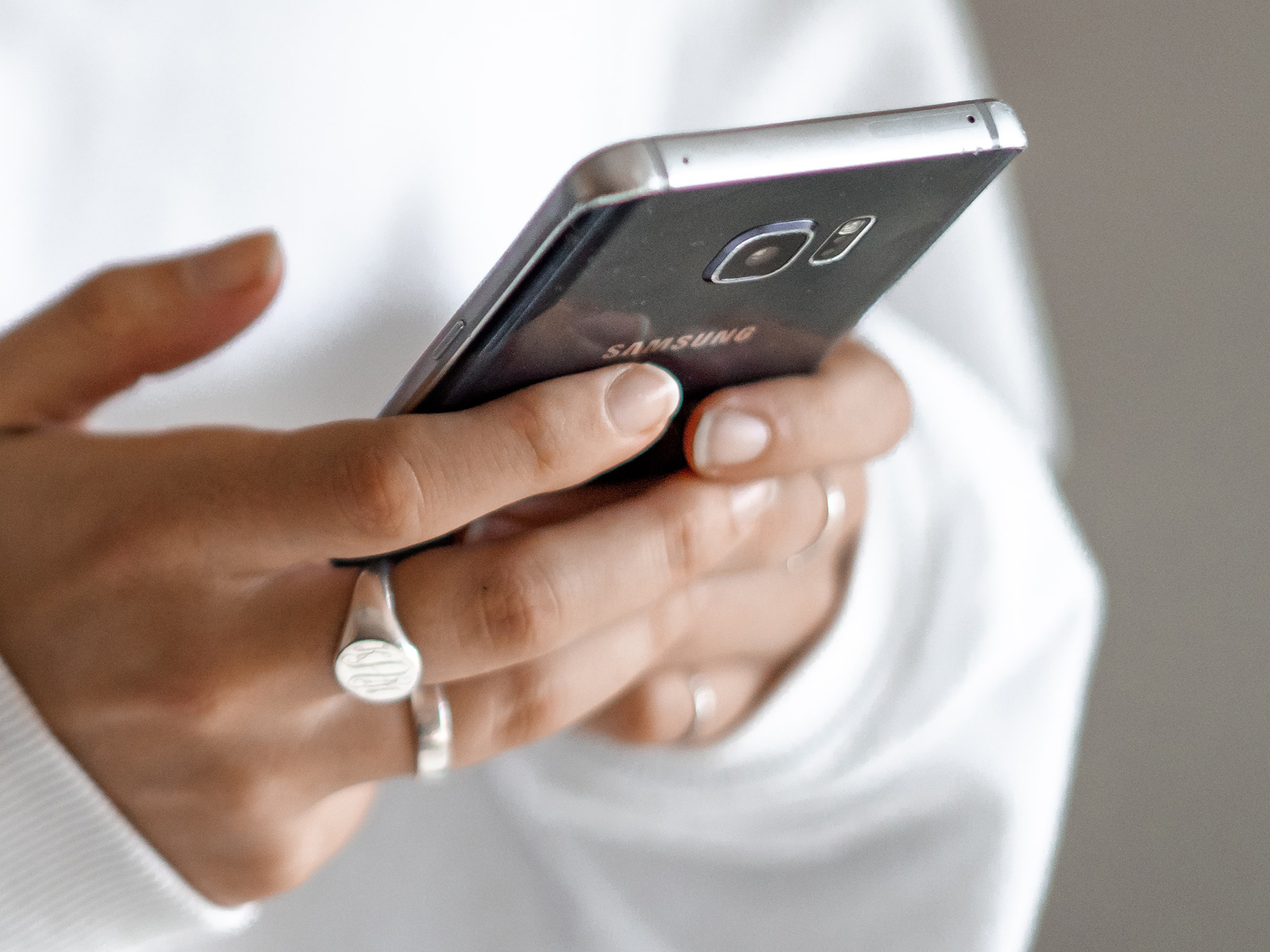 A person holding a black Android phone, possibly setting it to file transfer mode to back up their photos to their laptop.