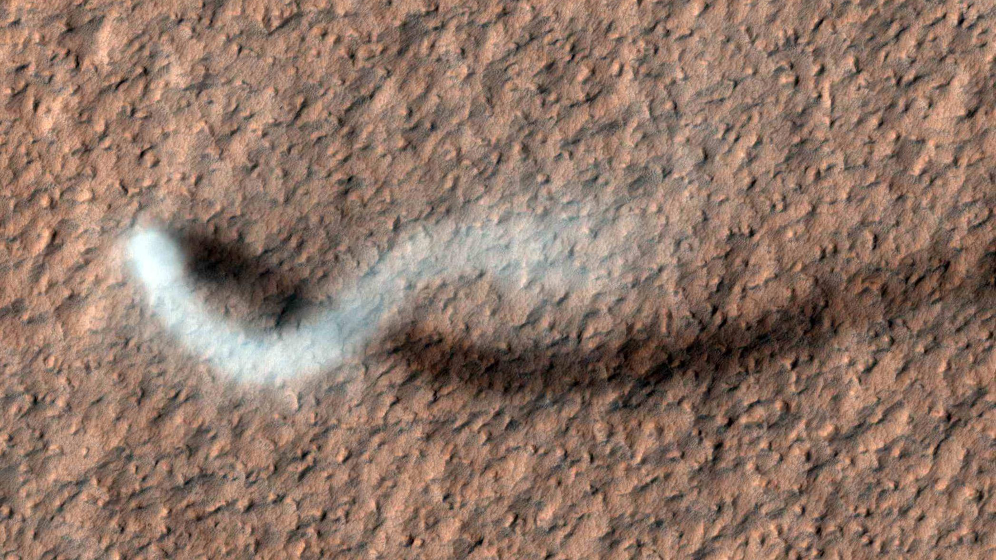 A towering dust devil casts a serpentine shadow over the Martian surface in this image acquired by the High Resolution Imaging Science Experiment (HiRISE) camera on NASA's Mars Reconnaissance Orbiter (April 2012).