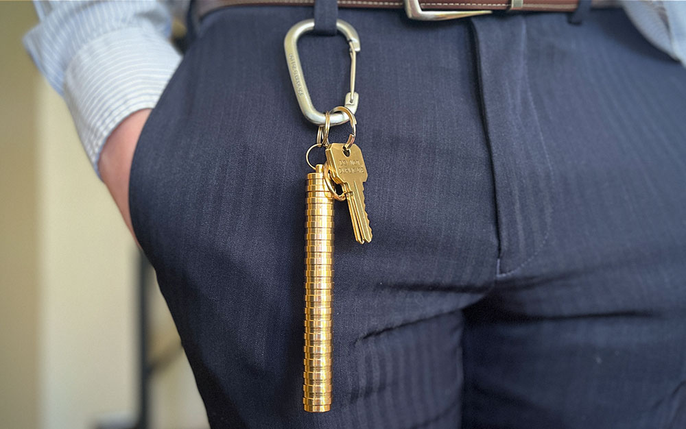 A person with blue pants with a gold joint holder on a carabiner.