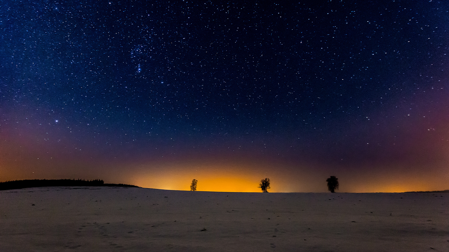 The night sky above a snowy field.