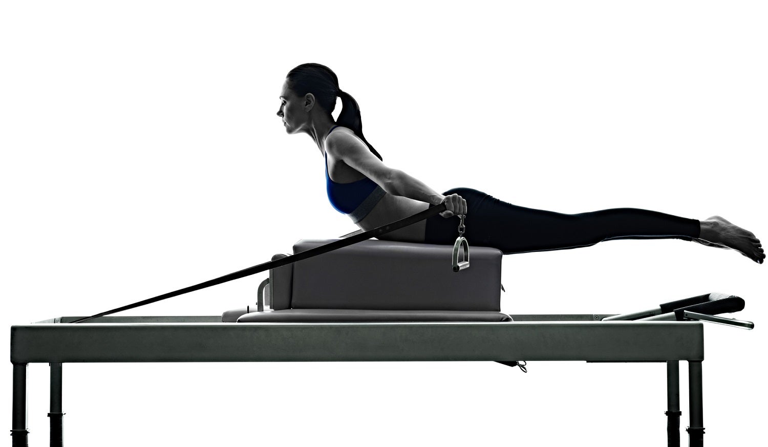Person in blue sports bra and leggings on stretching their back on a Pilates reformer machine