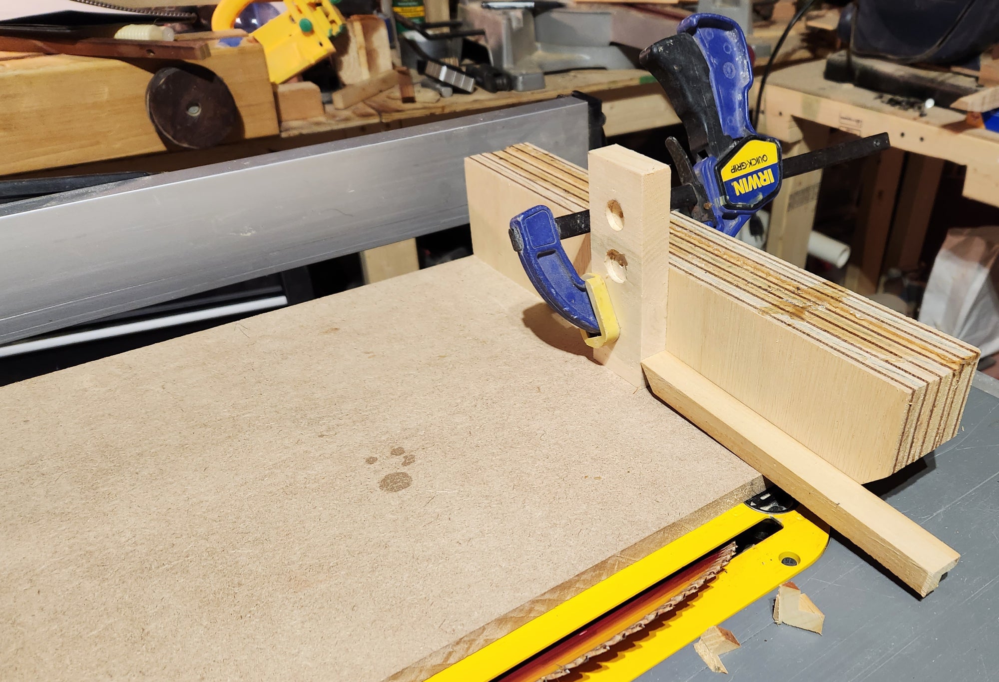 A table saw set at a 45-degree angle, being used to cut DIY picture frame pieces at mitered angles, with a stop block.