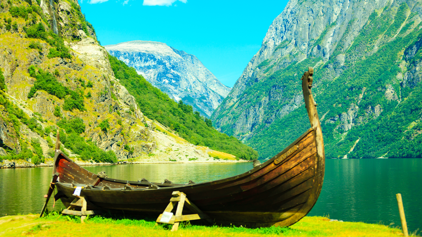 A lush green fjord in Norway with a wooden longship.