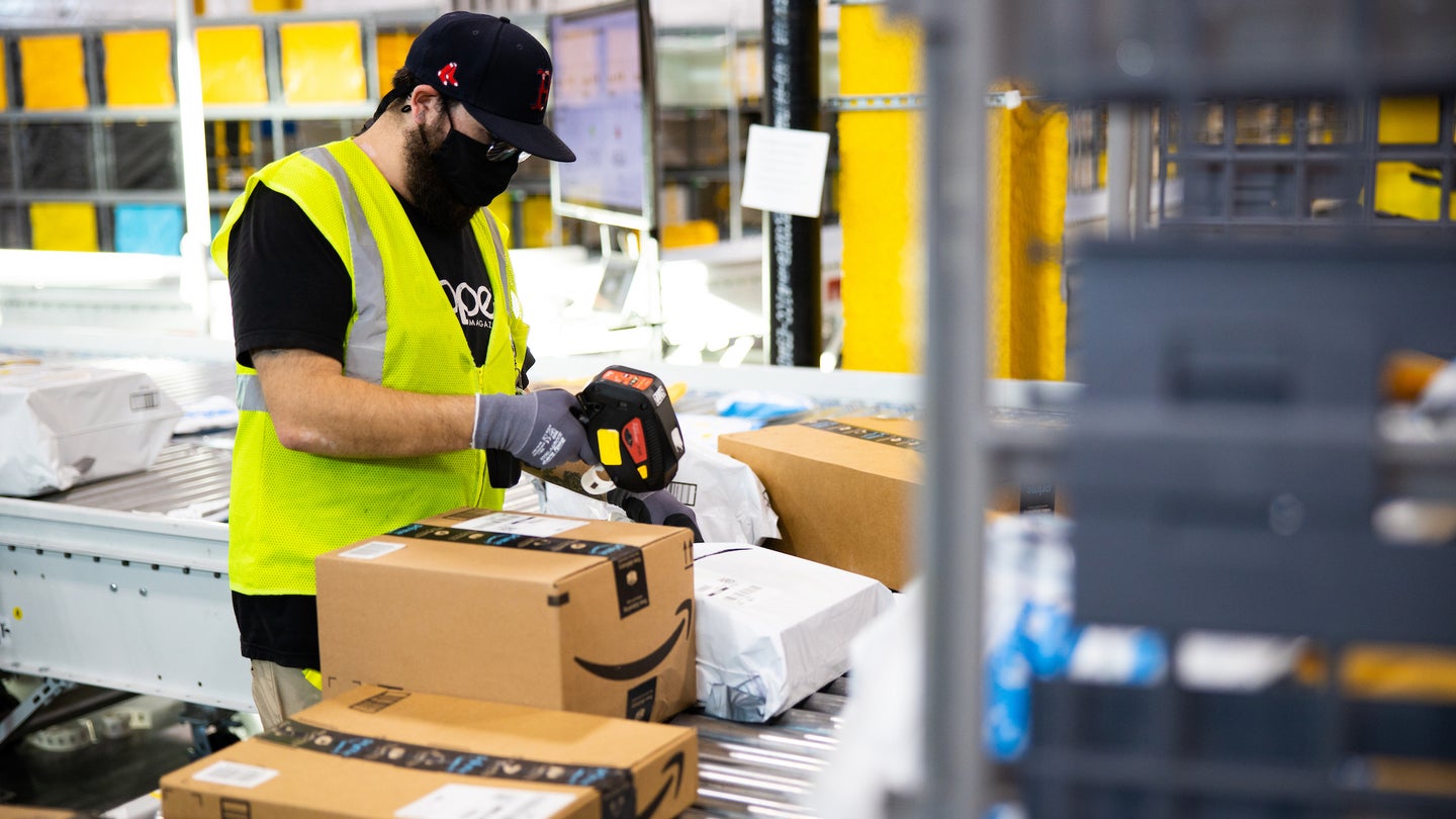 Amazon warehouse worker on assembly line boxing packages
