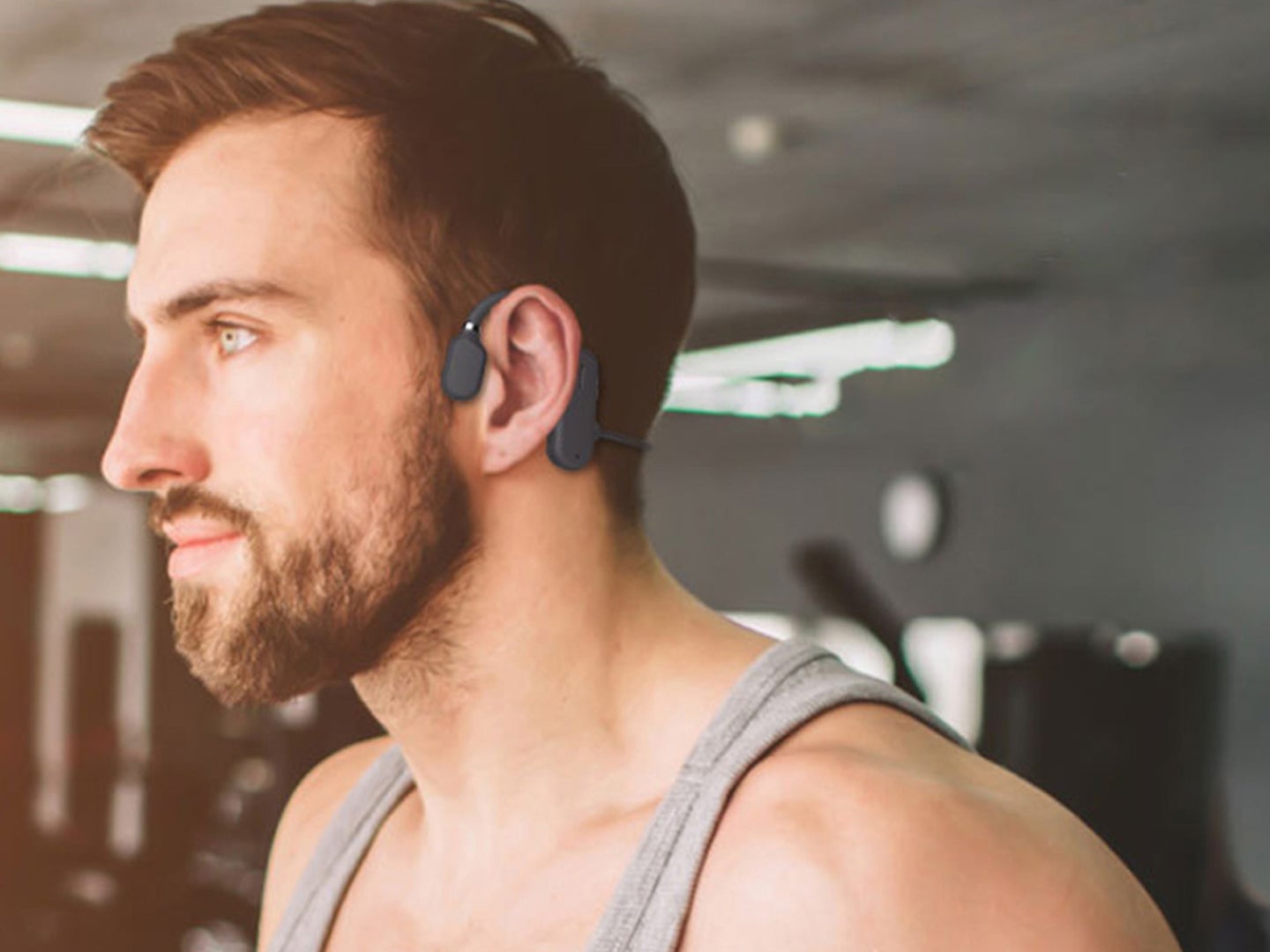 A person wearing bone conduction headphones in the gym