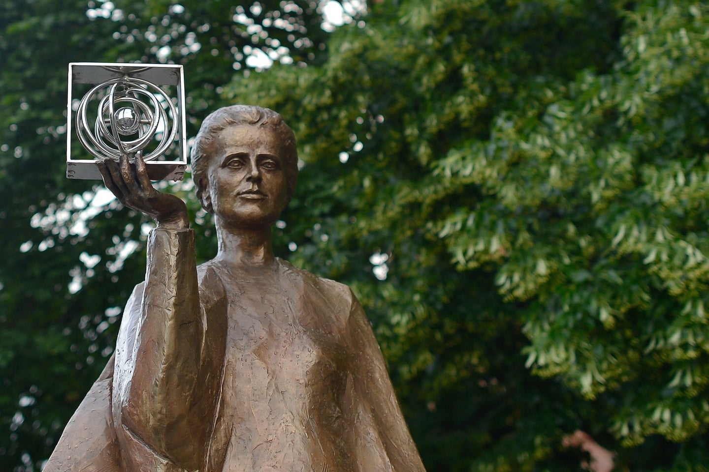 A bronze statue of chemist Marie Curie holding a model of the atom