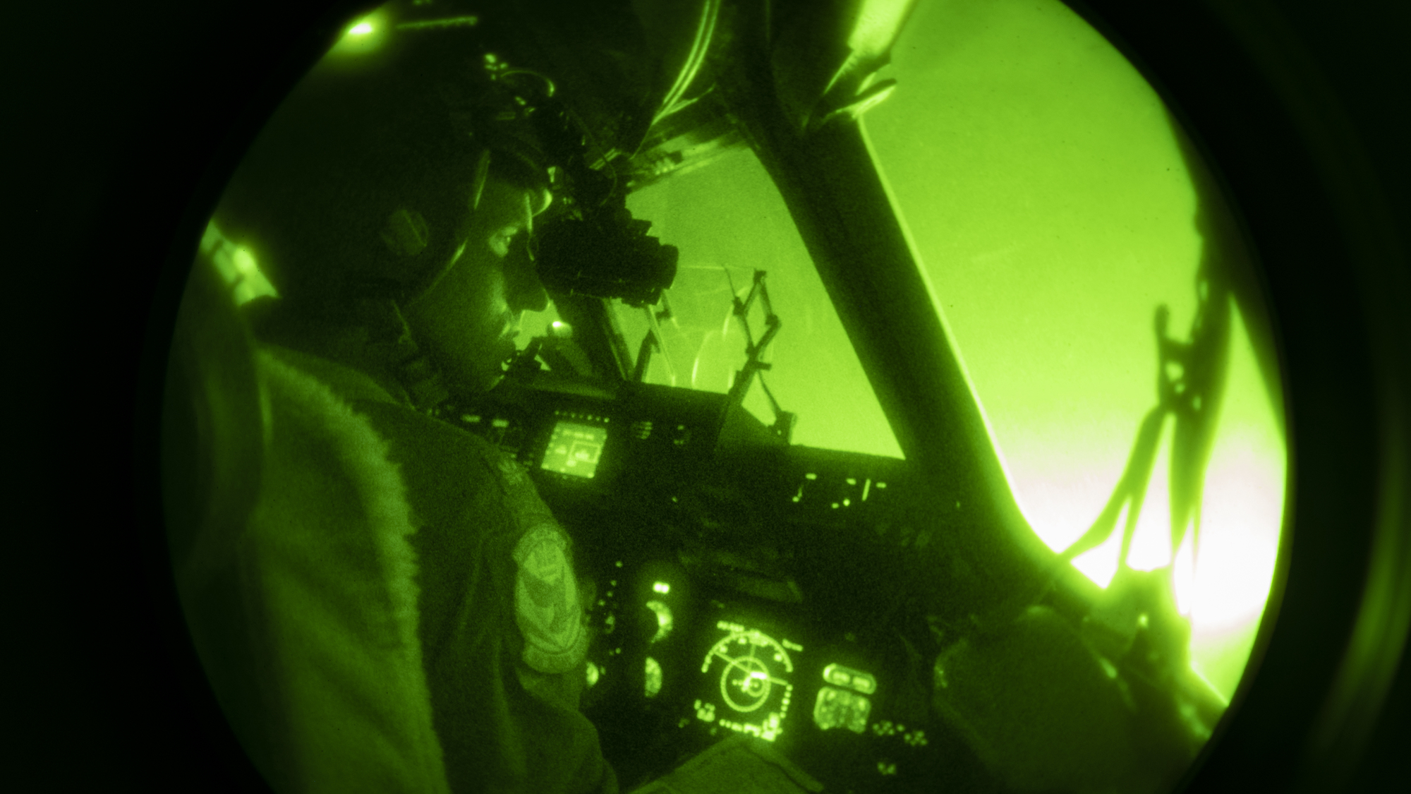 A night vision view of a C-17 pilot in the airplane's cockpit.