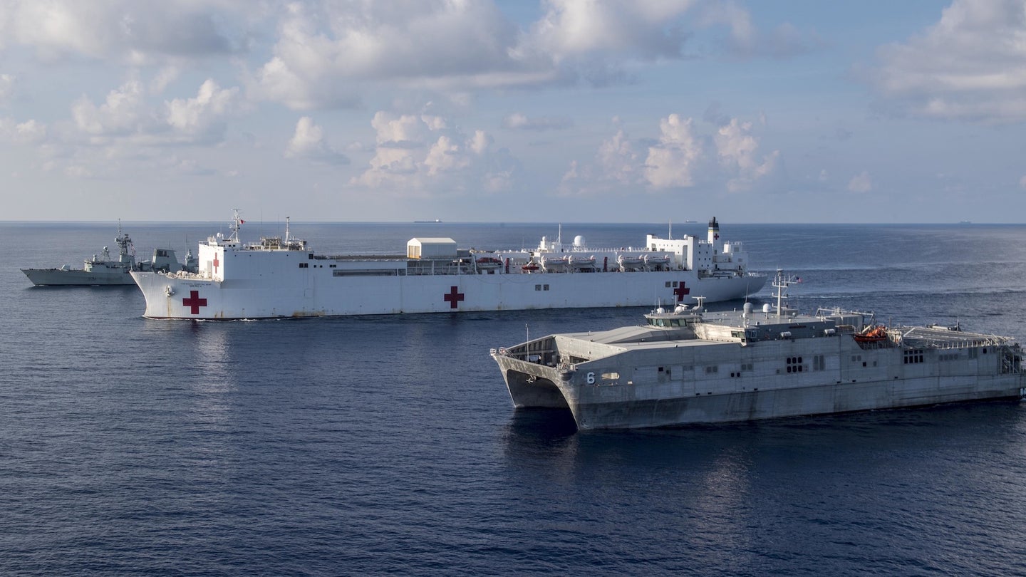 In the center is the USNS Mercy, while in the foreground is an expeditionary fast transport ship.
