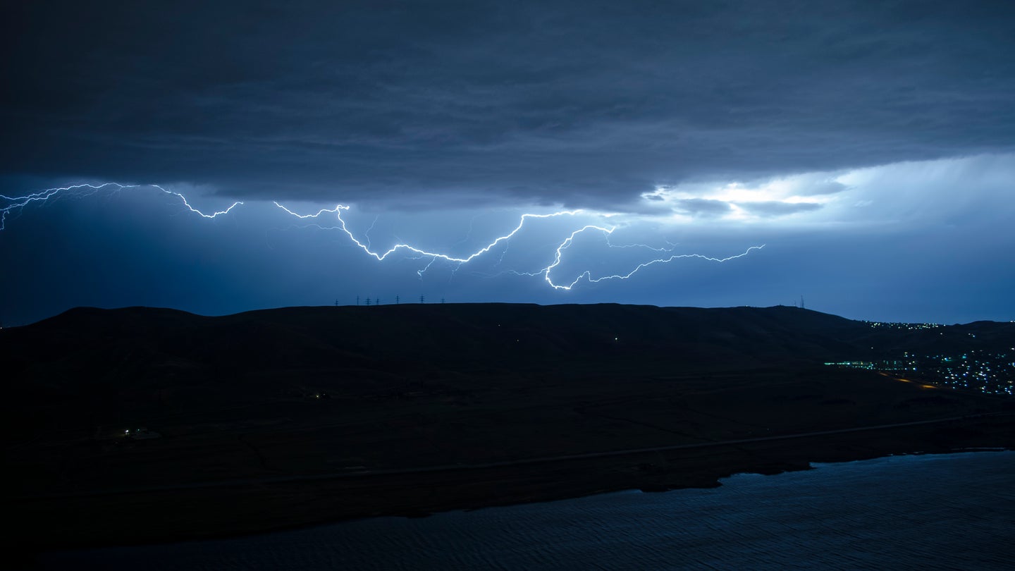 Lighting bolts across hills during thunderstorm