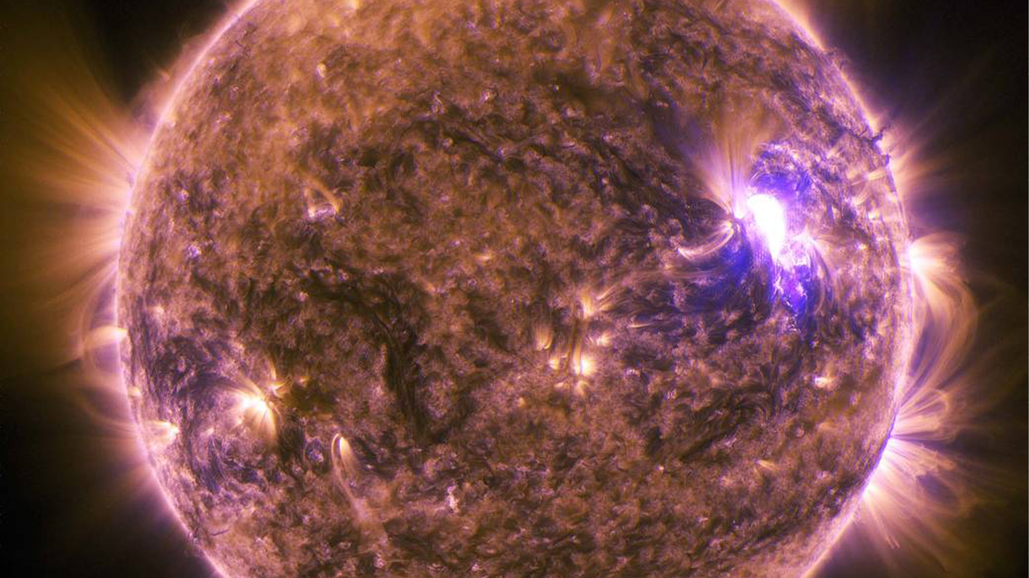 A solar flare with light and particles being released from the sun.