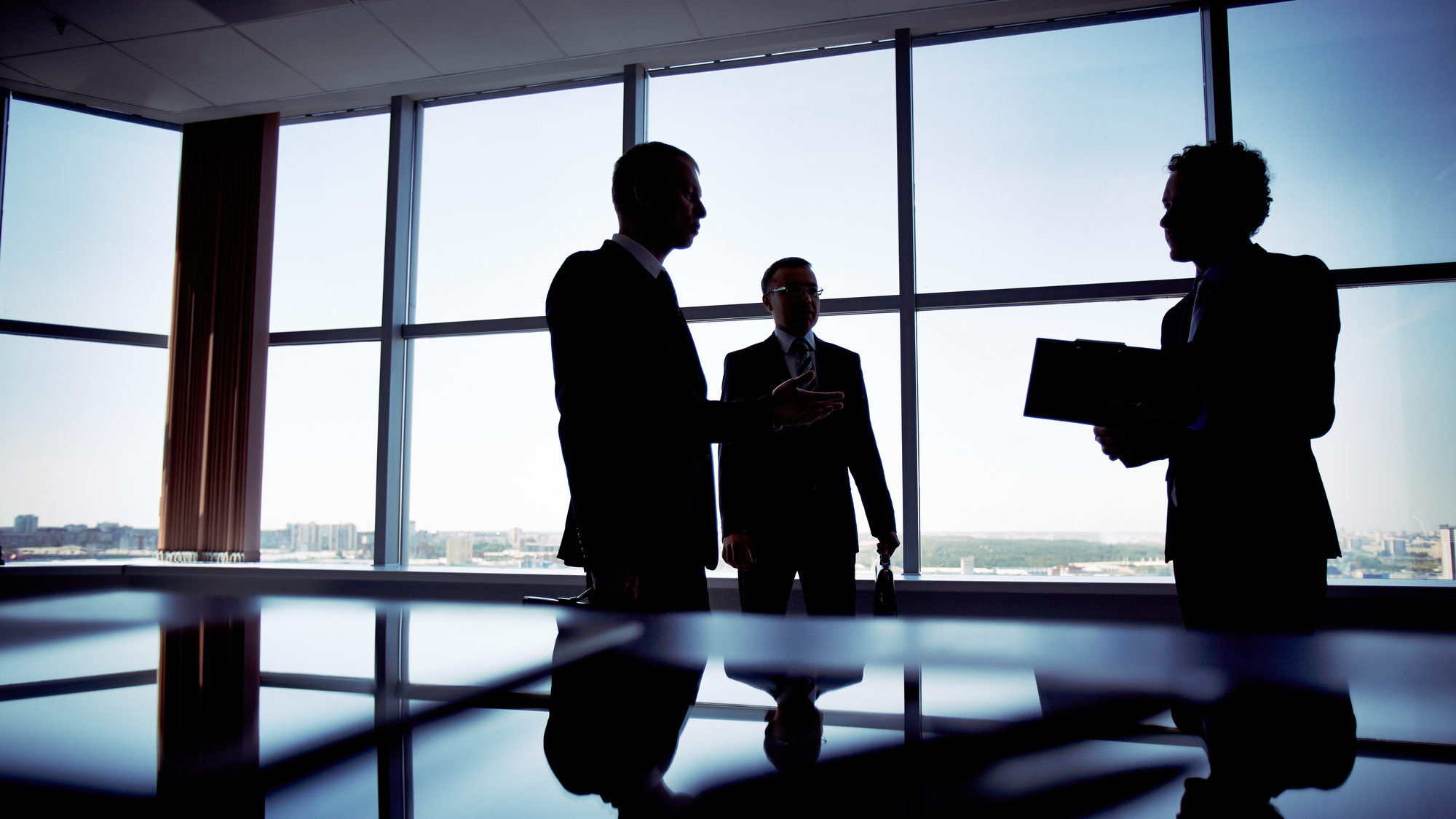Silhouette of three business executives in high rise conference room