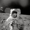 Apollo 12 astronaut on moon holding lunar sample to help determine how old the Earth is.